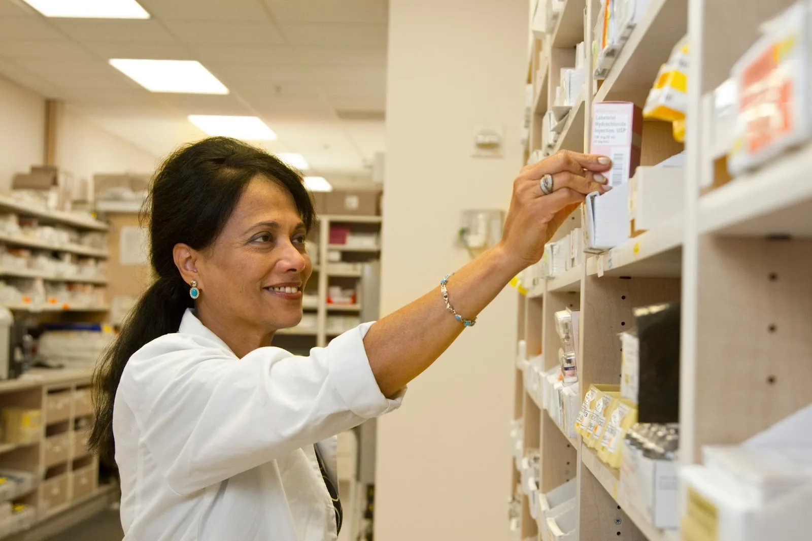 Pharmacienne en blouse blanche dans son officine, illustration du cas de Nathalie après la cession de ses officines
